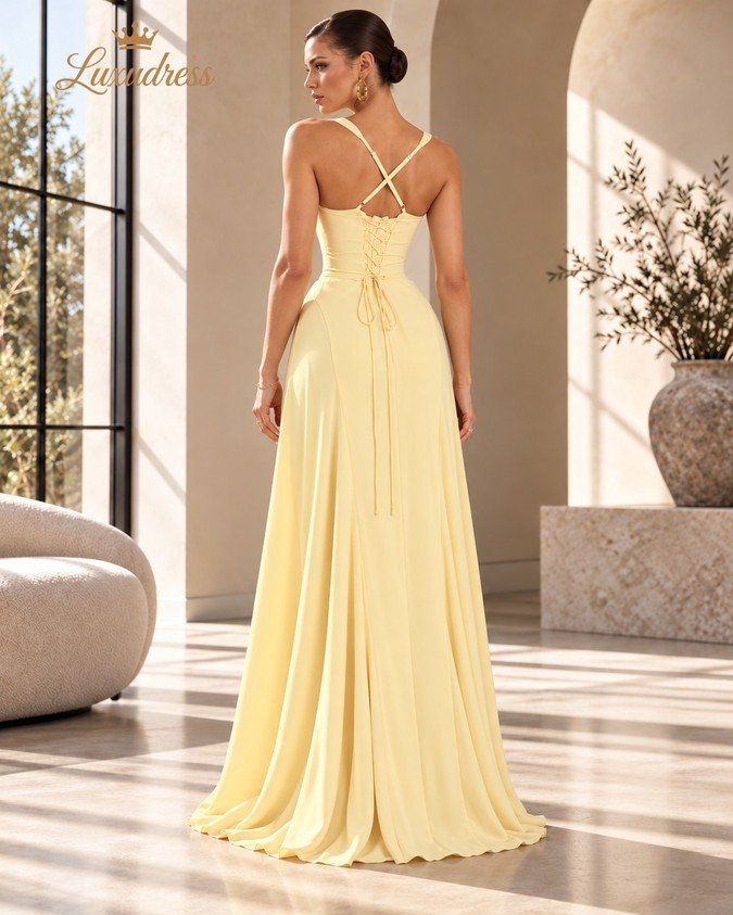 Back view of a butter yellow prom dress showing crossover straps, a lace-up corset back and a flowing floor-length skirt.