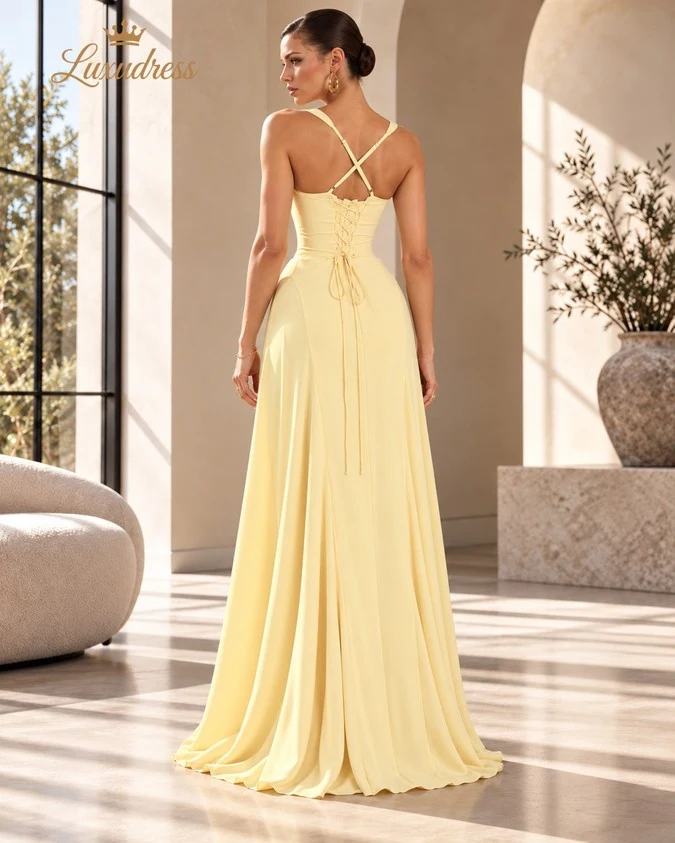 Back view of a butter yellow prom dress showing crossover straps, a lace-up corset back and a flowing floor-length skirt.