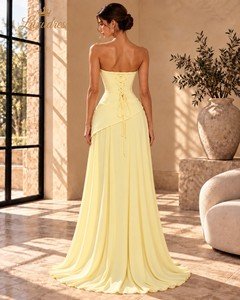 Back view of a butter yellow evening gown showing a lace-up corset back, asymmetric waist overlay and long flowing skirt.