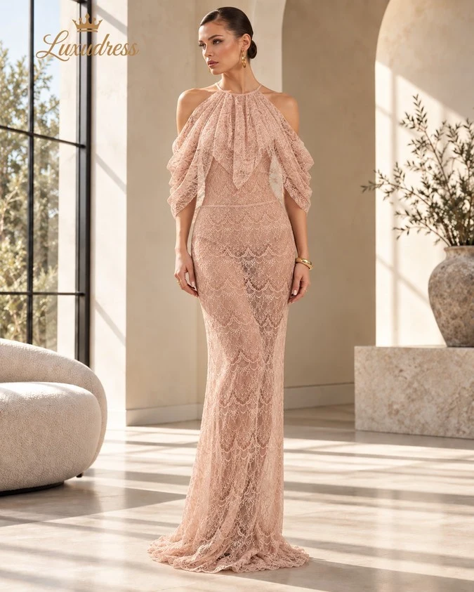 Front view of a blush pink halter lace evening gown with draped sleeves and a fitted floor-length silhouette.