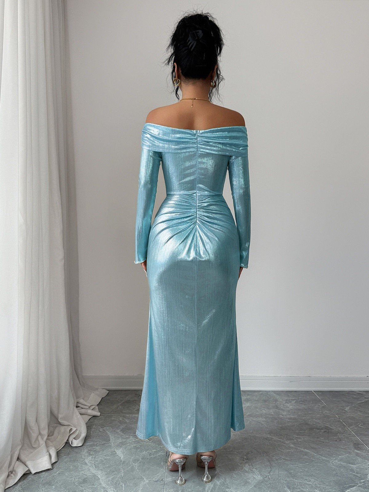 Back view of an ice blue metallic off-shoulder maxi dress with a ruched buckle waist.