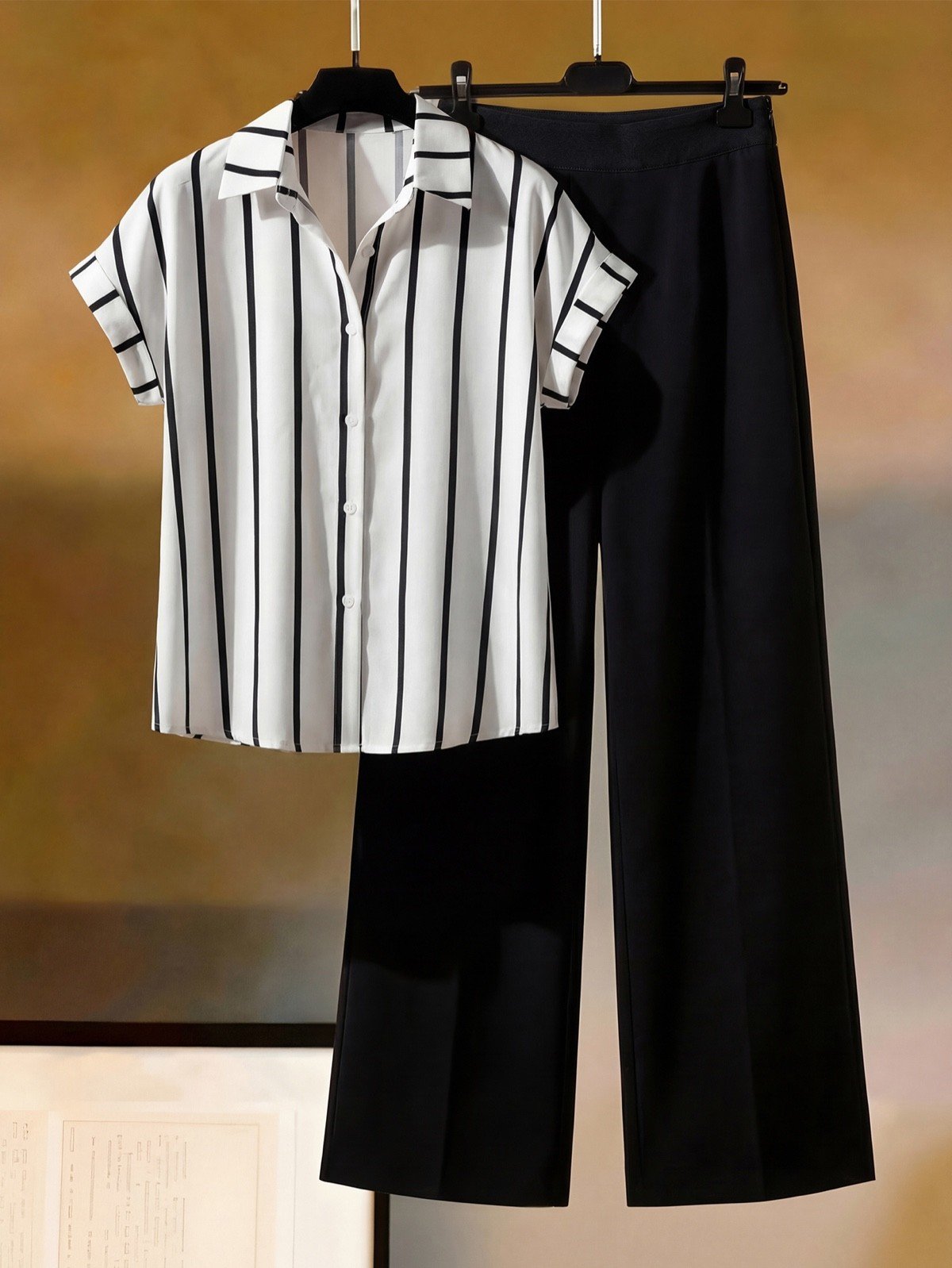 Hanger product display of a striped short-sleeve blouse and black wide-leg pants set.