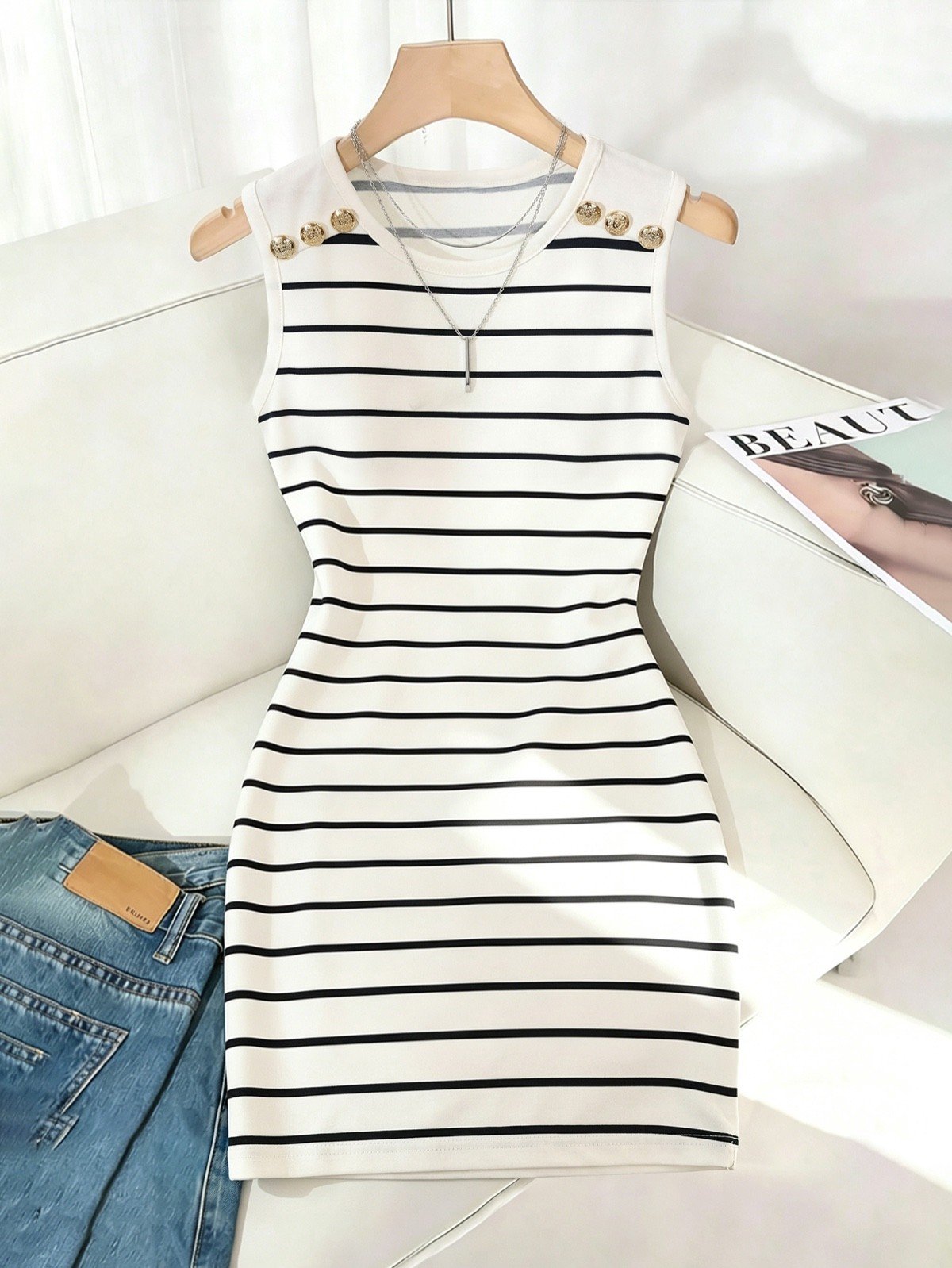 Styled flat-lay of a white striped knit bodycon mini dress with gold-tone shoulder buttons.