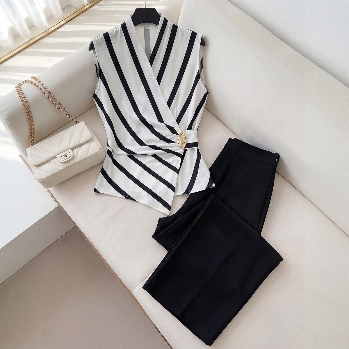 Sofa set flat-lay of a striped wrap blouse and black wide-leg pants set with buckle detail.
